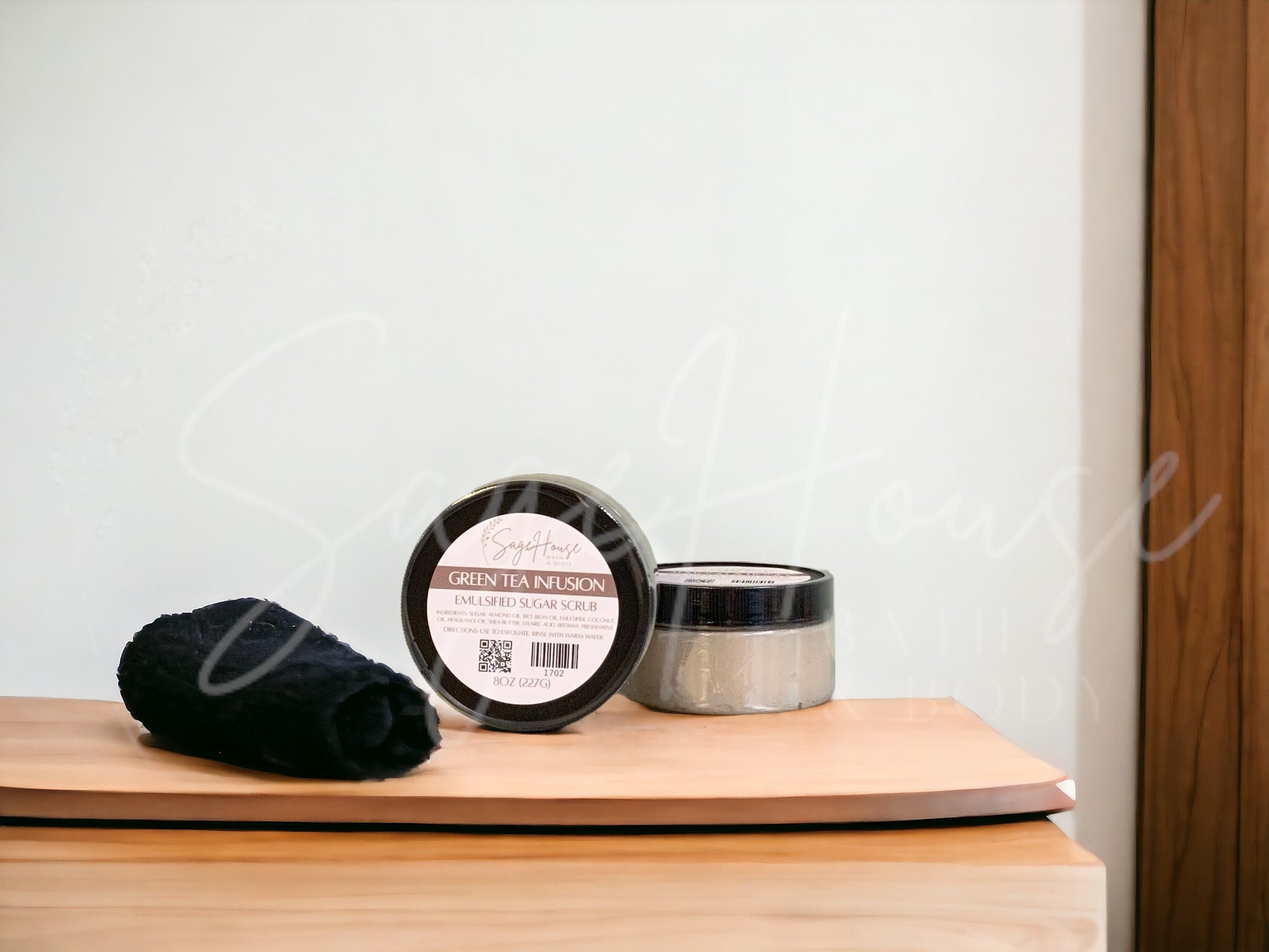 Two jars of scrub, one standing next to the other, sitting on a wooden surface with a white background