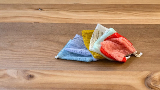 A group of Soap Scrub Pouches in various colors placed on a wooden surface.