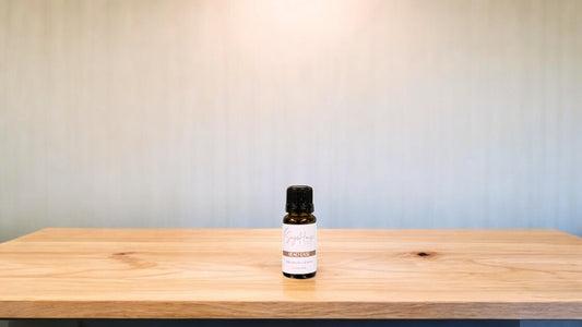 A small bottle of head ease essential oil is placed on a wooden surface with a plain background.