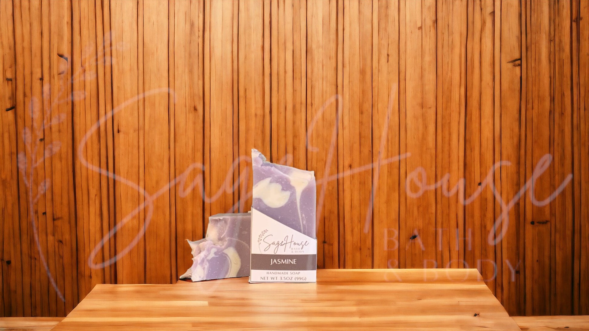 A purple colored bar of soap with white accents in a white labeled box, on a wood surface.