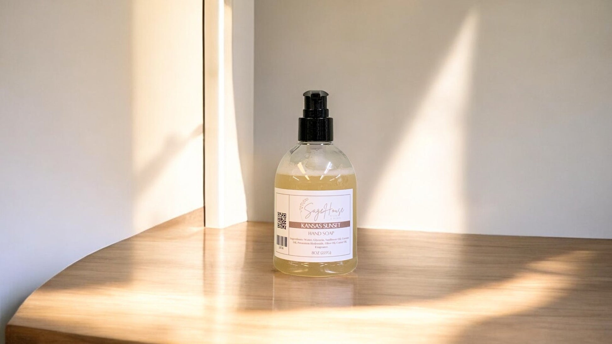 A clear plastic bottle of hand soap with a black cap, placed on a wooden surface with natural lighting.