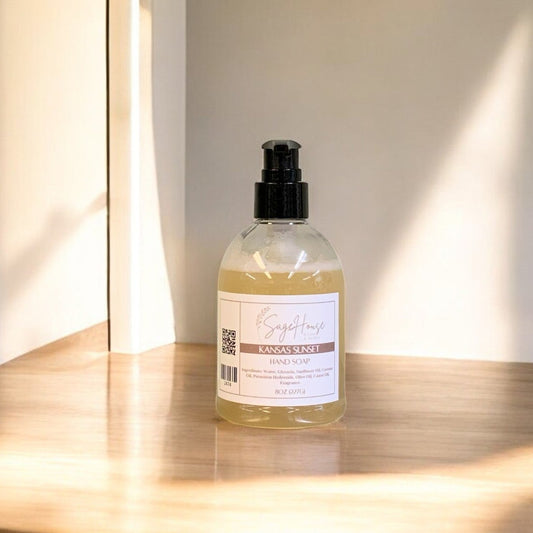 A clear plastic bottle of hand soap with a black cap, placed on a wooden surface with natural lighting.