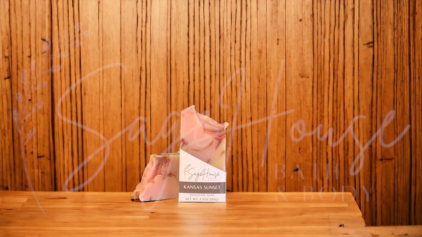 A peach colored bar of soap with yellow and red accents in a white labeled box, on a wood surface.