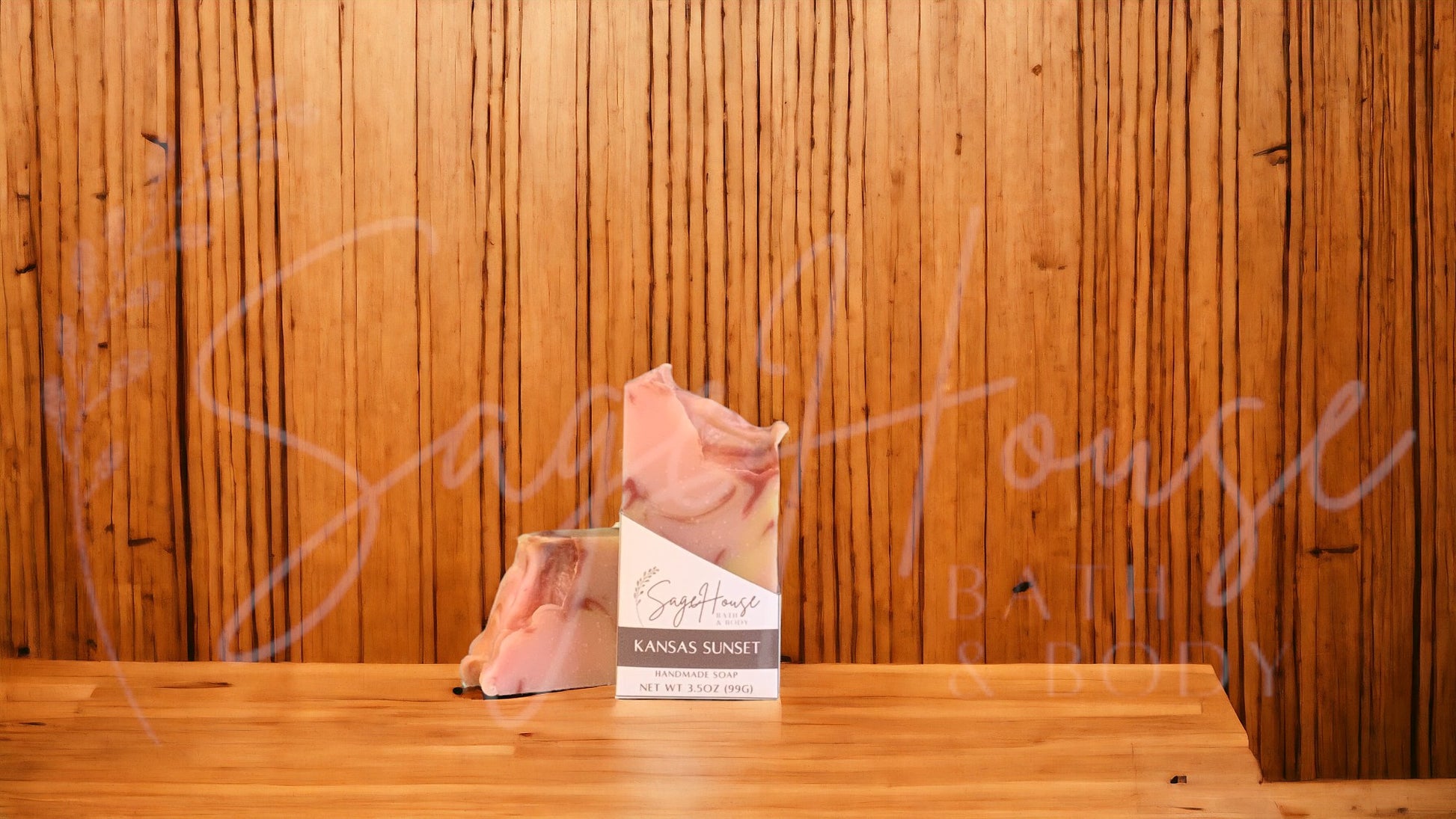 A peach colored bar of soap with yellow and red accents in a white labeled box, on a wood surface.