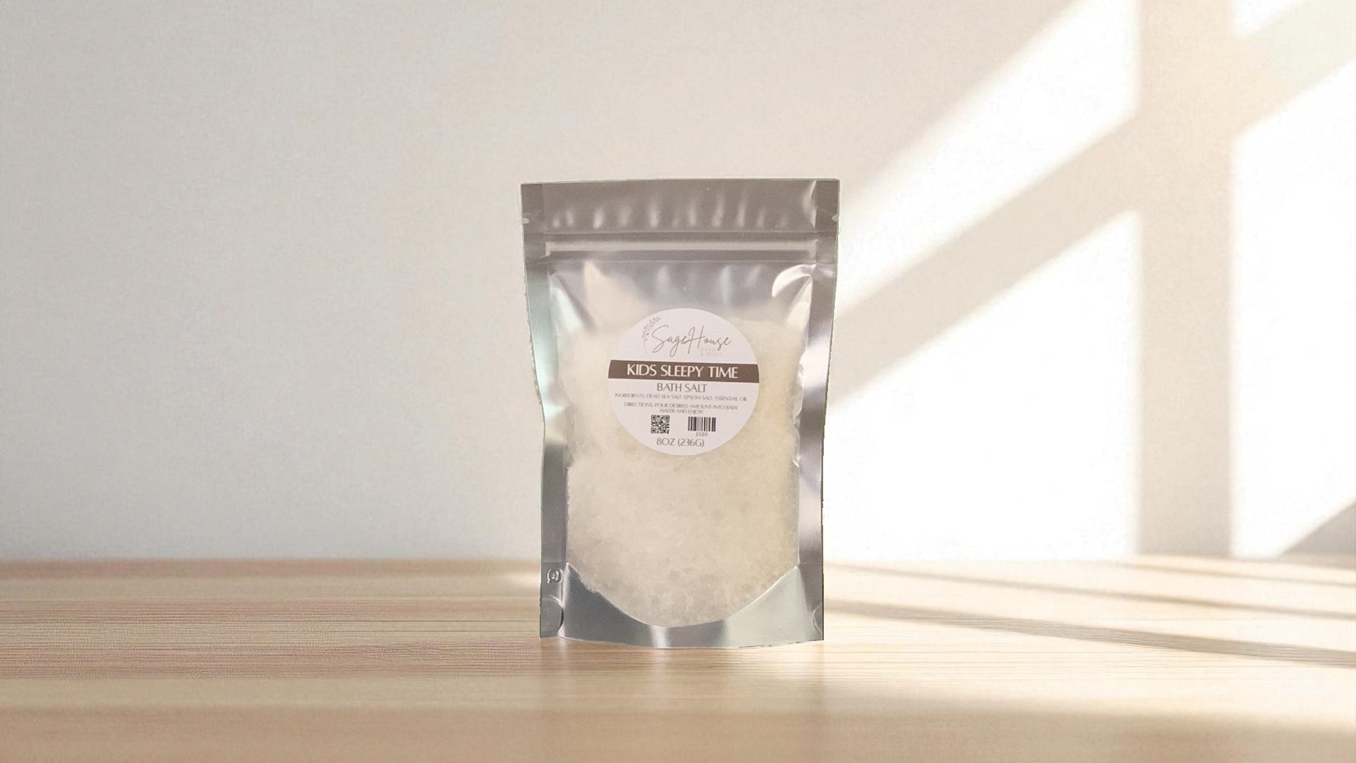 Silver packaging with a clear window of white salt labeled "kids sleepy time" on a wood surface.