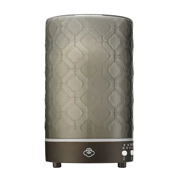 A modern electric aromatherapy diffuser with a pattern on the glass cover, featuring control buttons at the base.