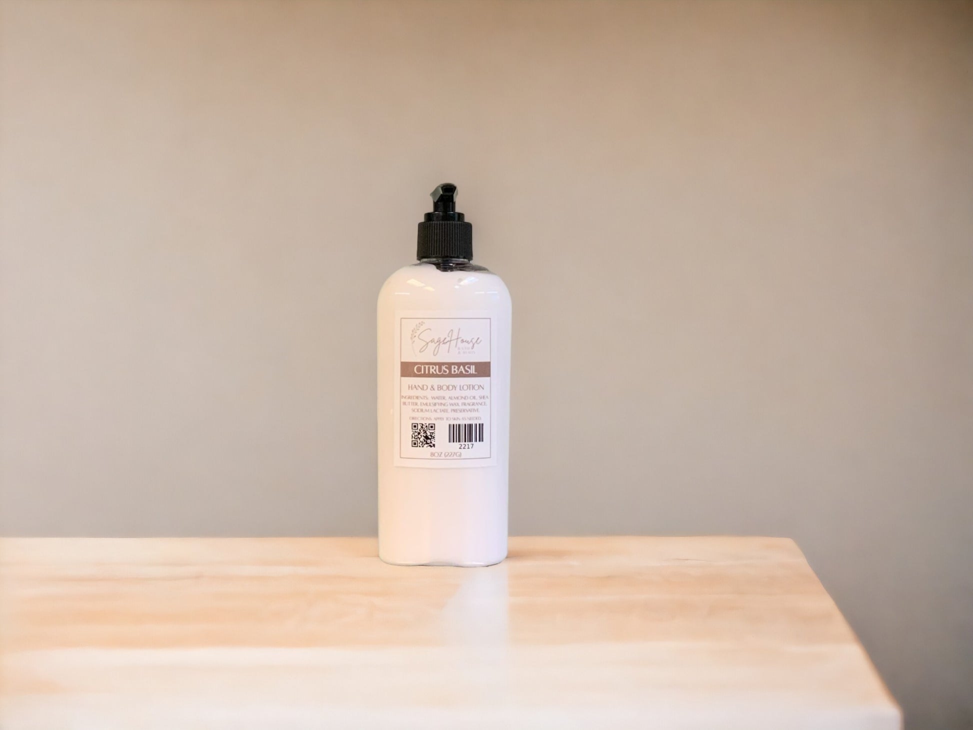 A large bottle of lotion, sitting on a light wood surface, with a tan background. 