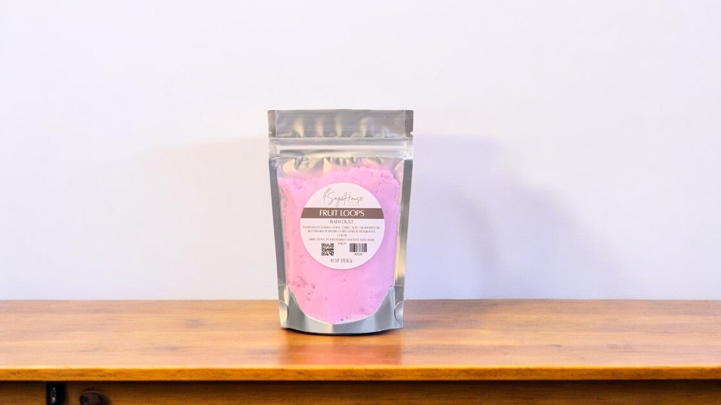 A clear plastic pouch packaging a purple-colored bath bomb or dust, labeled 'fruit loops'. The pouch is placed on a wooden surface.