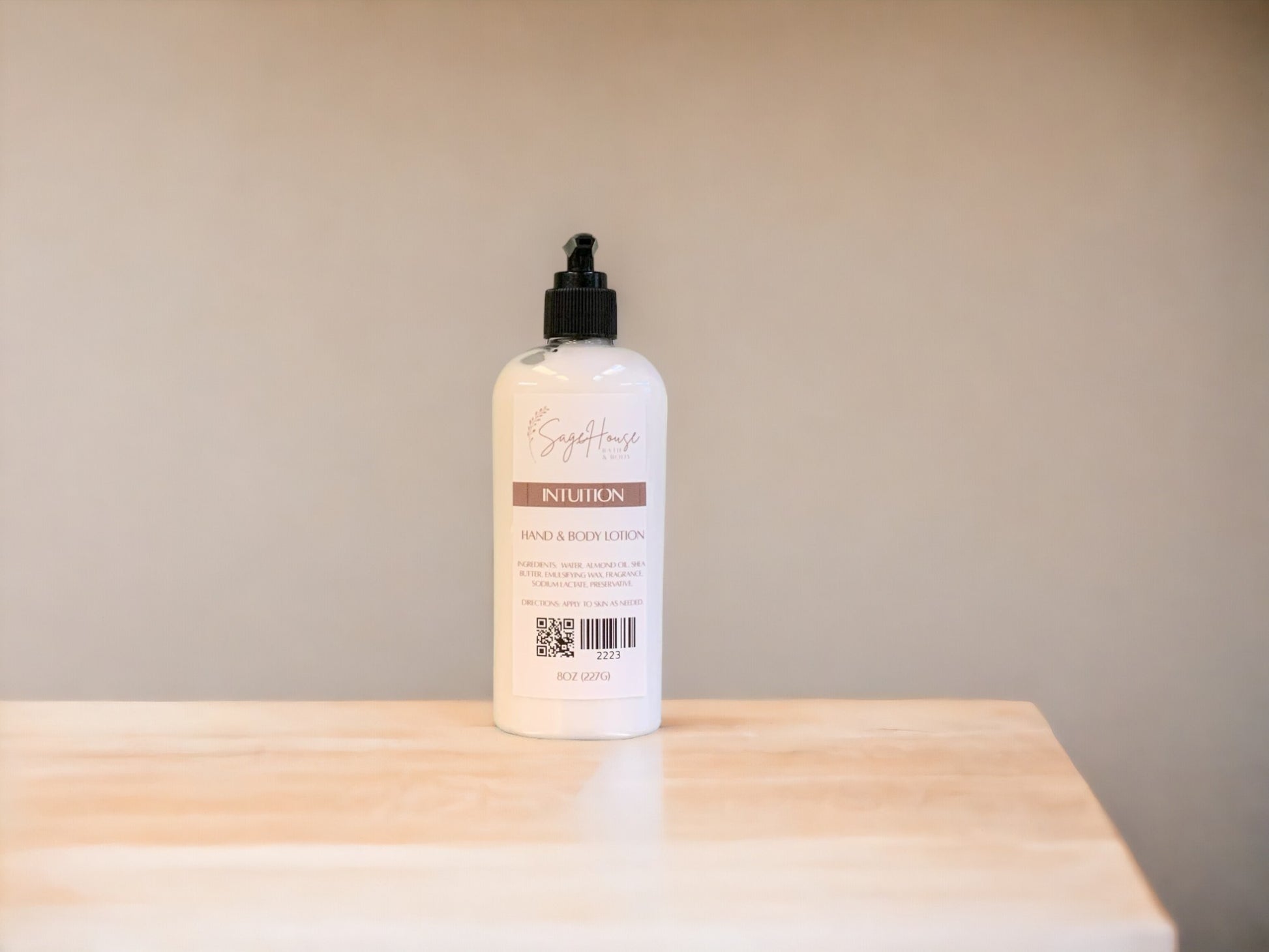 A large bottle of lotion, sitting on a light wood surface, with a tan background. 