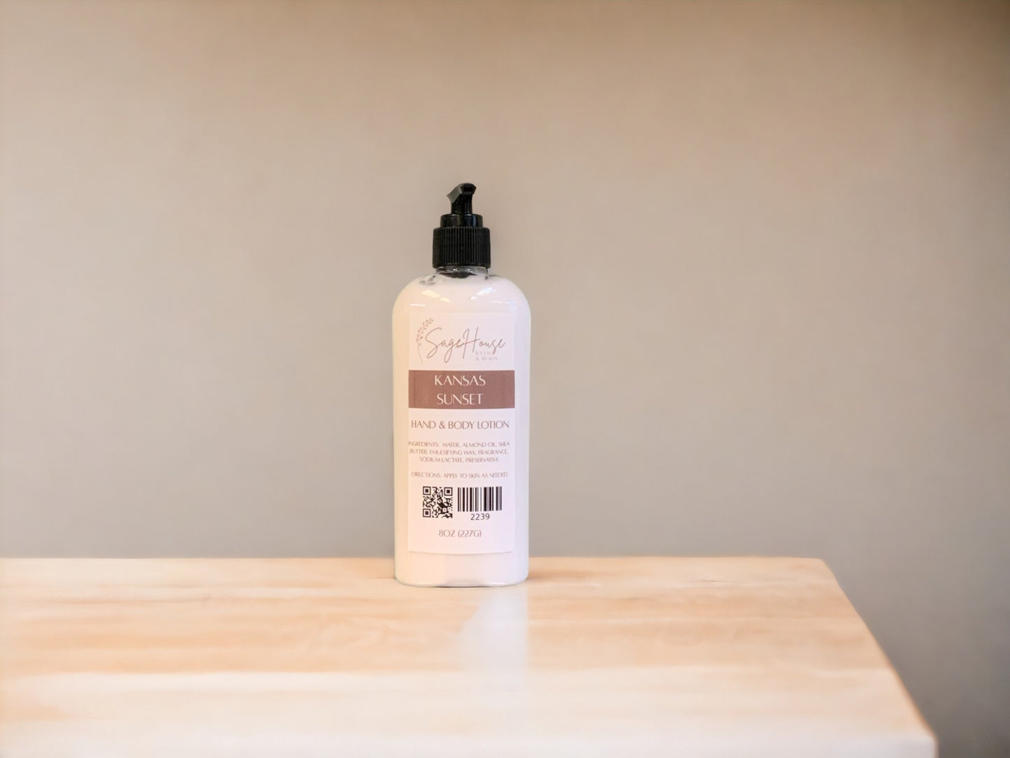 A larrge bottle of lotion, sitting on a light wood surface, with a tan background.