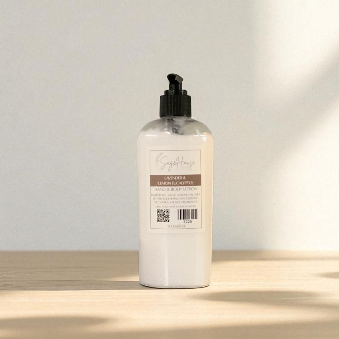 White bottle of lotion with black pump top on a light wooden surface with a blurred white background