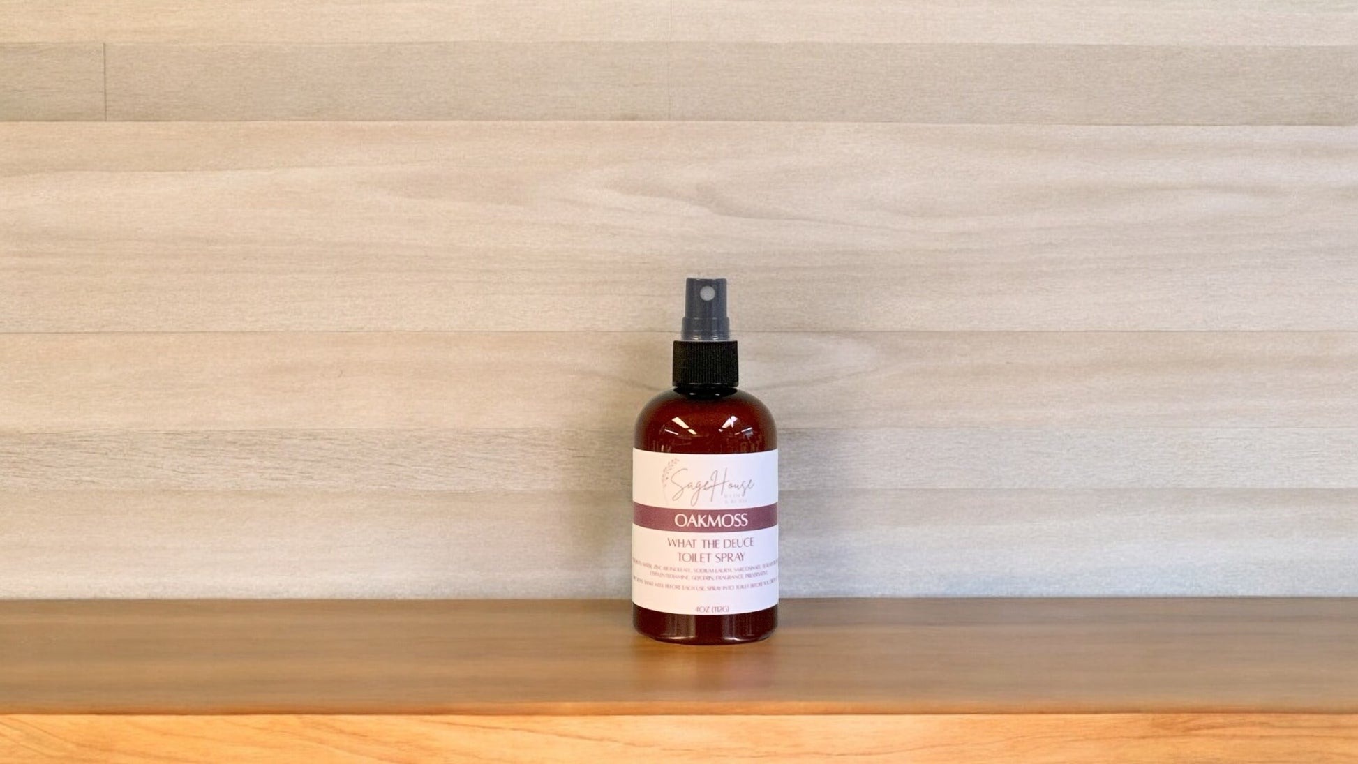 Amber colored spritz bottle with oakmoss label, on wood surface