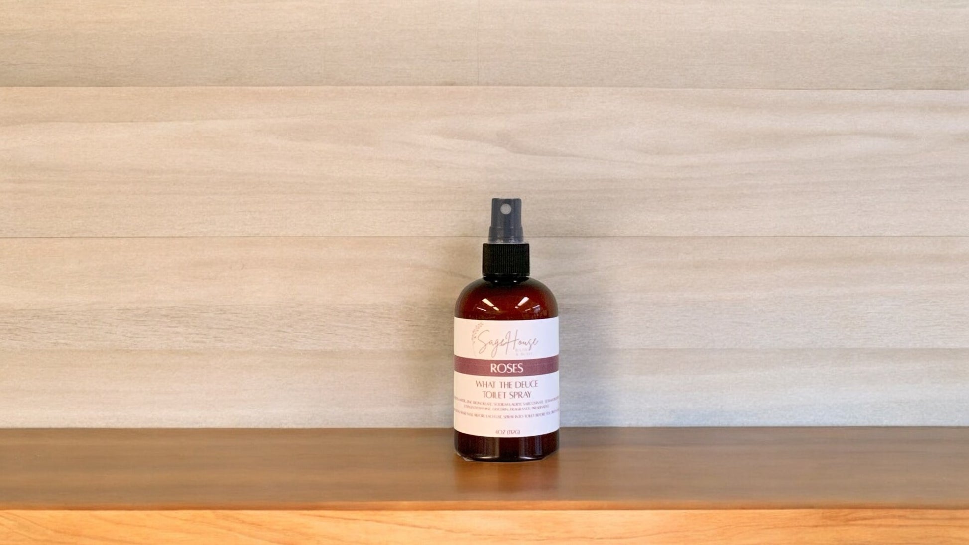 Amber colored spritz bottle with roses label, on wood surface