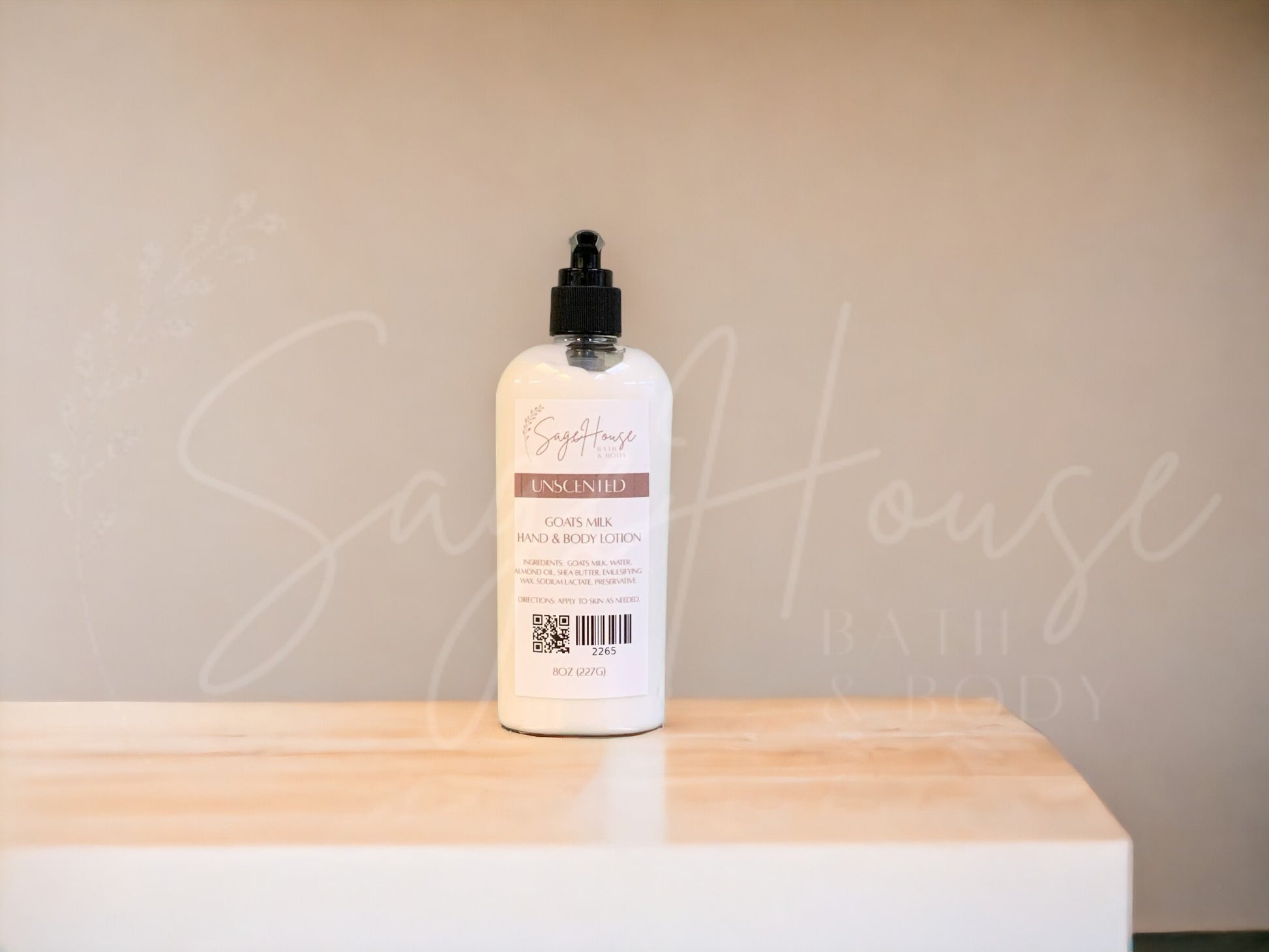 A large bottle of lotion, sitting on a light wood surface, with a tan background. Has SageHouse logo inlayed