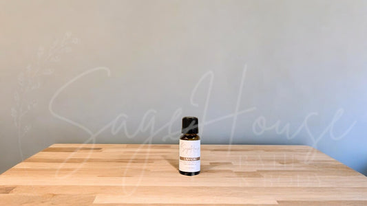 A small bottle of lavandin essential oil is placed on a wooden surface with a plain background.