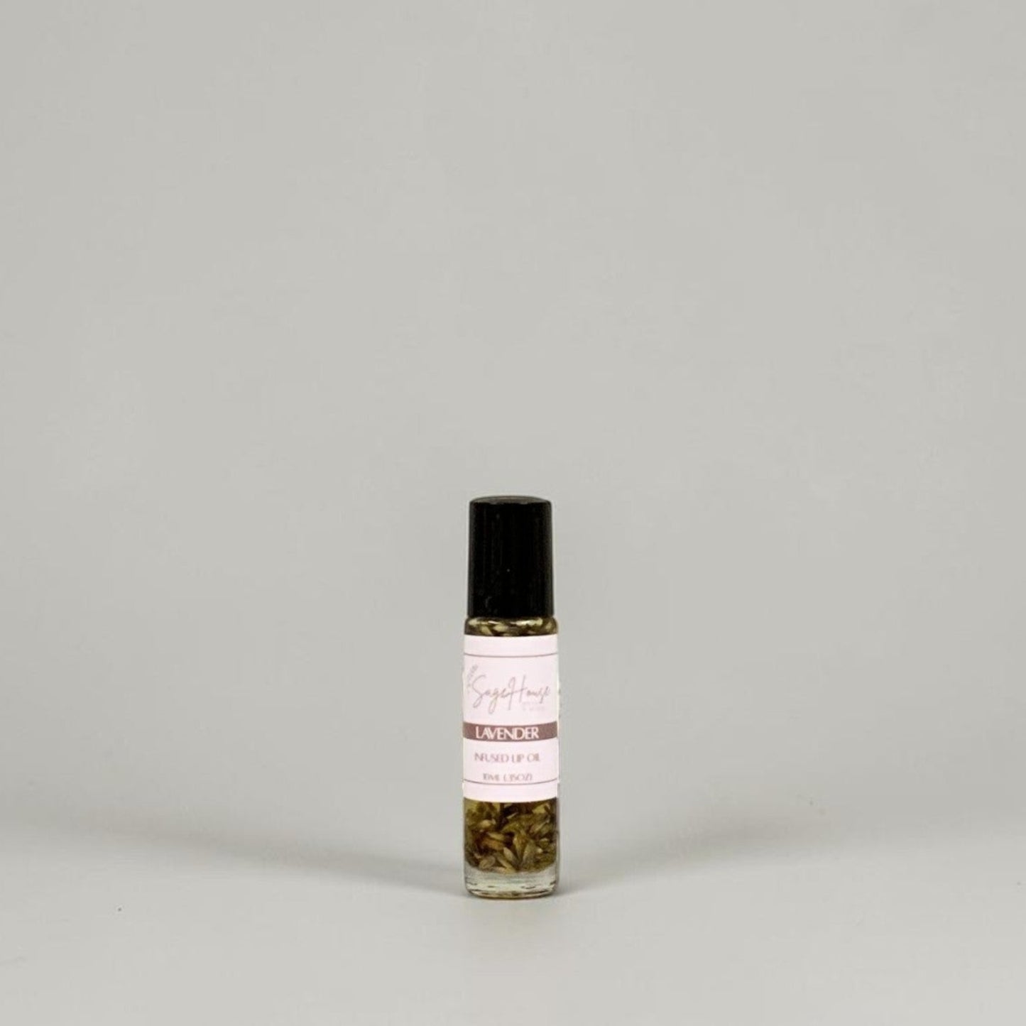 A small glass roller bottle with a black cap and a white label, standing on a light gray background.