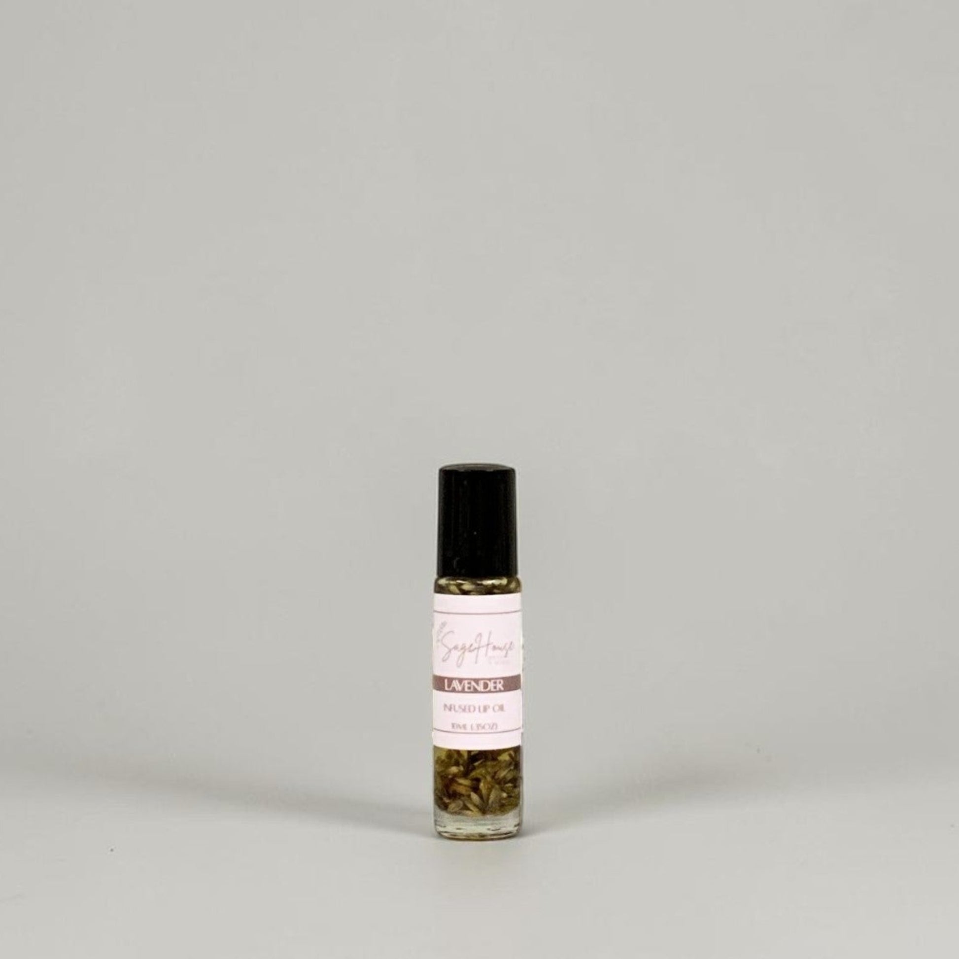 A small glass roller bottle with a black cap and a white label, standing on a light gray background.
