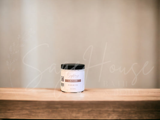 A jar of Lavender Body Butter placed on a wooden surface with a neutral background.