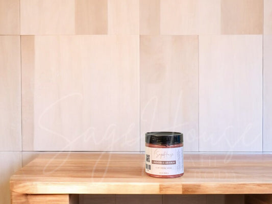 A face mask product in a small container, with a beige background resembling a wooden texture.