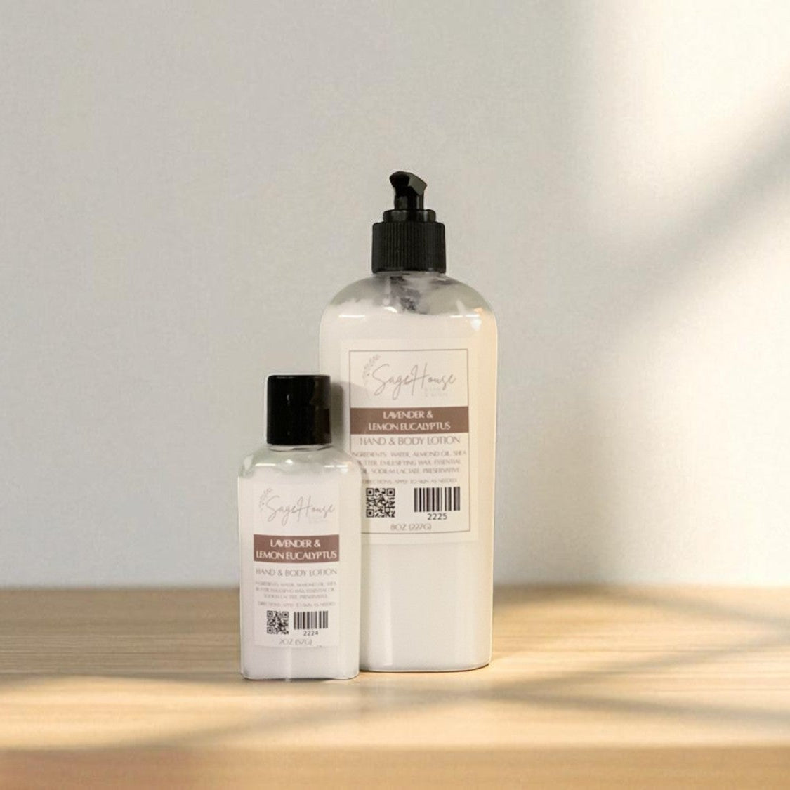Two white bottles of lotion with black cap and black pump top on a light wooden surface with a blurred white background