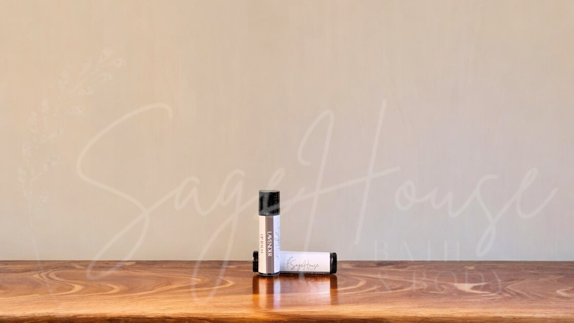A tube of lavender lip balm placed upright with a tube lying behind it, on a wooden surface.
