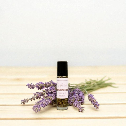 Small bottle of lip oil with purple flowers surrounding, on a light background
