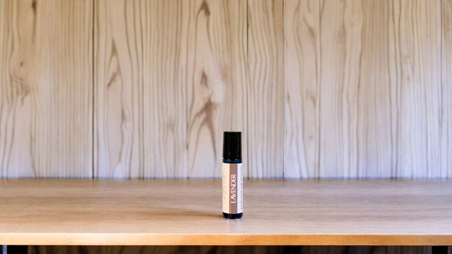 A roller bottle, labeled with 'lavender Massage Oil', positioned on a wooden surface.