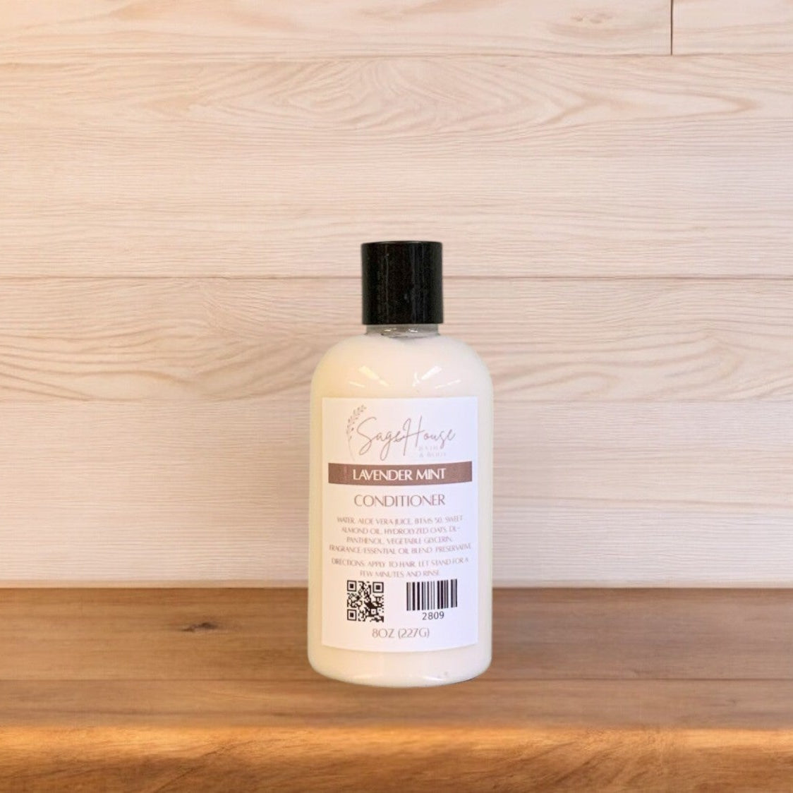A bottle of Lavender Mint conditioner in a clear bottle on a wooden surface.