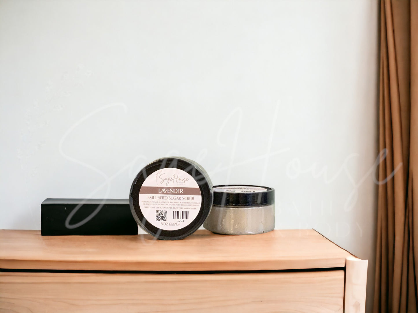 Two jars of scrub, one standing next to the other, sitting on a wooden surface with a white background