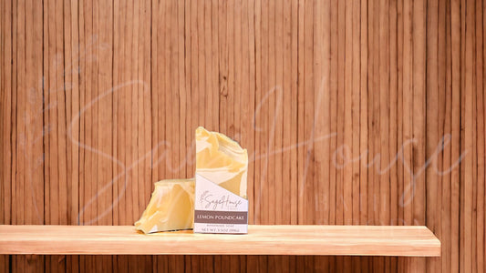 A yellow bar of soap with white accents in a white labeled box, on a wood surface.