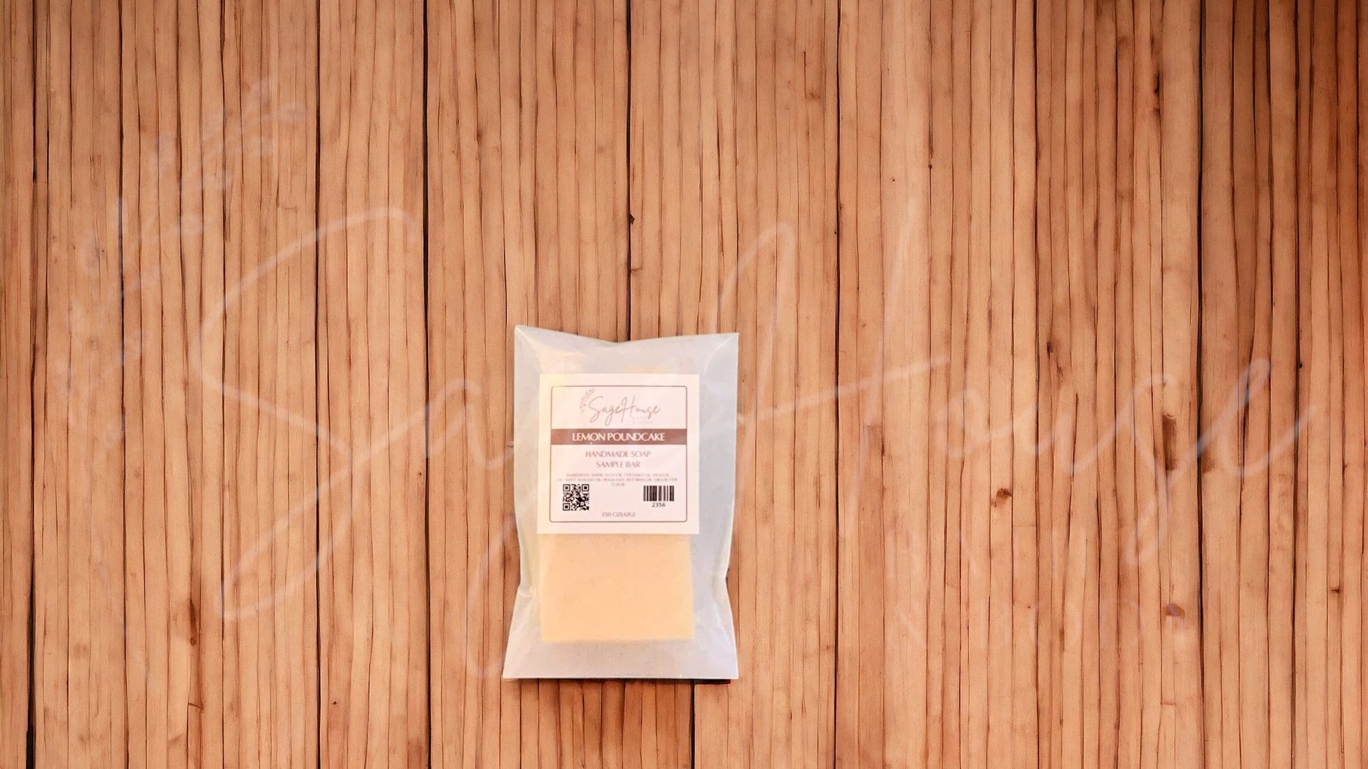 A sample bar of soap in a glassine bag. placed on a wood surface.