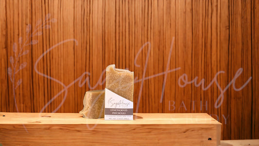 A tan bar of soap in a white labeled box, on a wood surface.