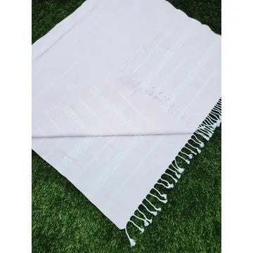 Light Pink Turkish cotton towel, folded onto itself, Laying on grass, on a white background.