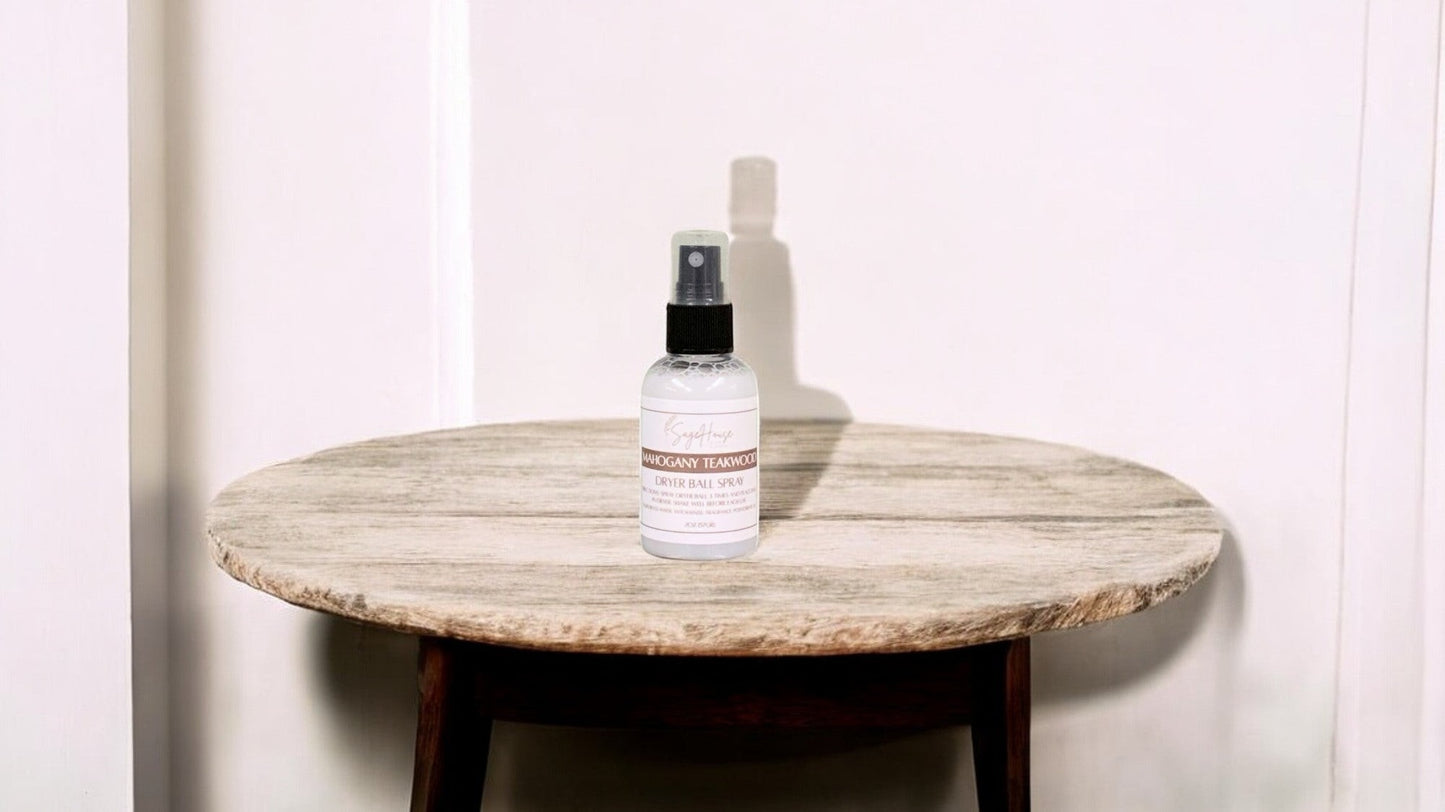 A clear bottle with black spritz top. sitting on a stone table with a white wall in the background