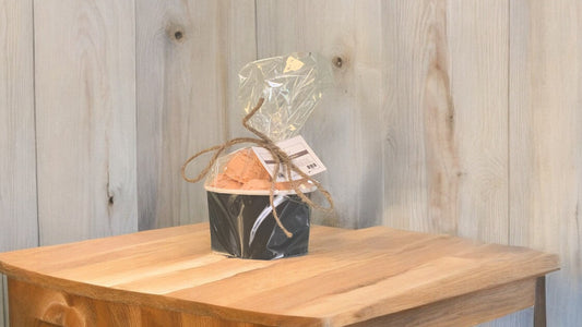 A set of bath truffles, wrapped in clear packaging with a decorative ribbon. placed on a wooden surface.