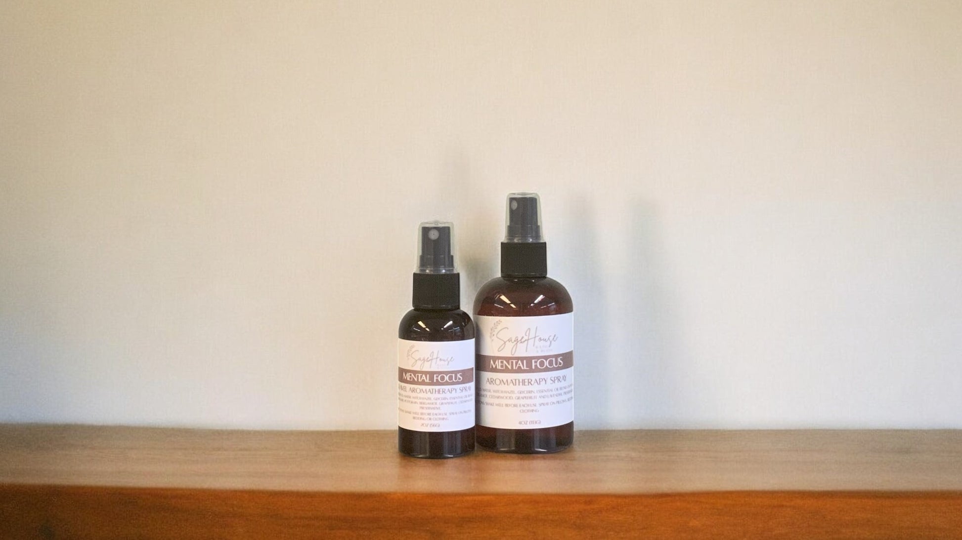 Amber colored spritz bottles in two sizes, with mental focus label, on wood surface. Sold individually.