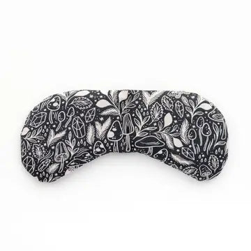 An eye mask therapy pack with a mushroom and foliage design on a dark blue fabric. displayed on a white background.