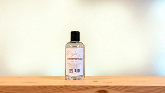 Bottle of "oatmeal milk & honey" body wash on a wooden surface with a light background