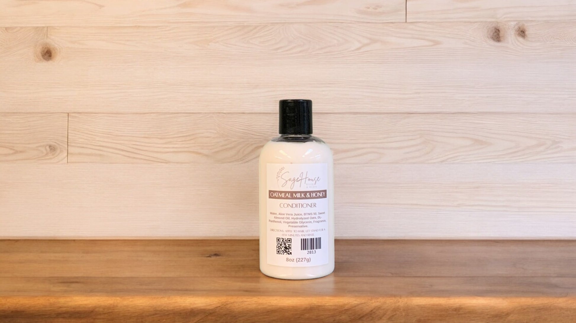 A bottle of conditioner with a black cap. Sitting on a wood surface with a light wood background