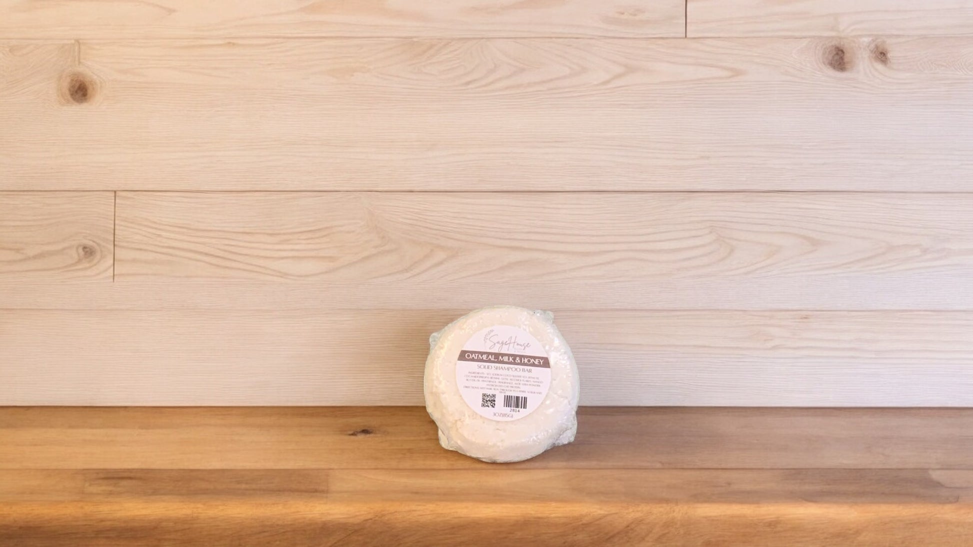 An Oatmeal Milk & Honey shampoo bar, placed on a wooden surface.