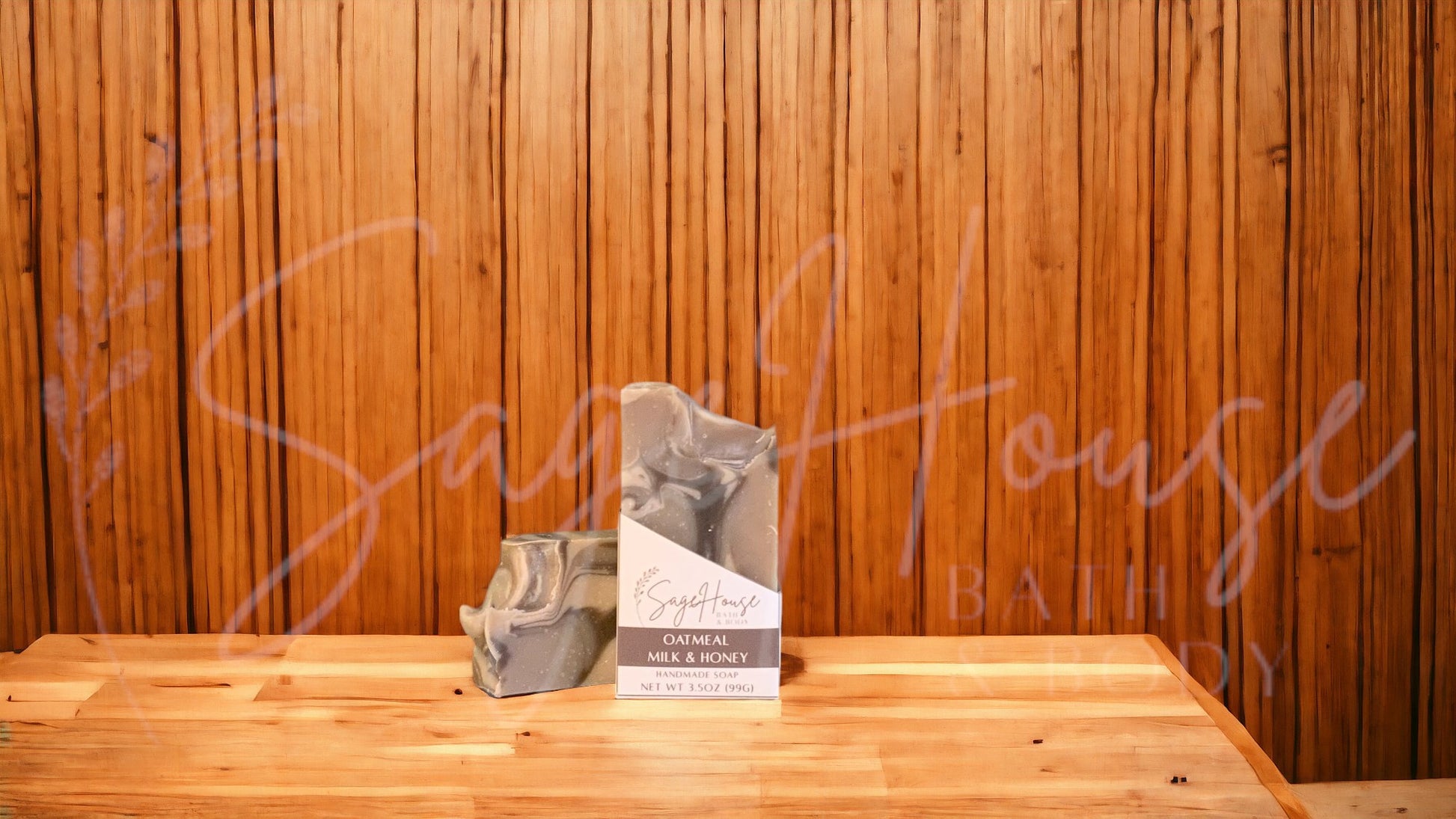 A tan bar of soap with accents of dark brown and white, in a white labeled box, on a wood surface.