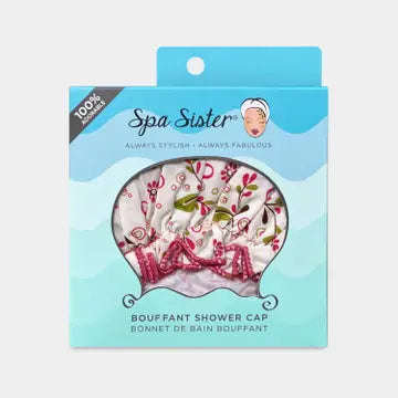 A pink shower cap with a flower and olive vine print, inside a package. on a white background