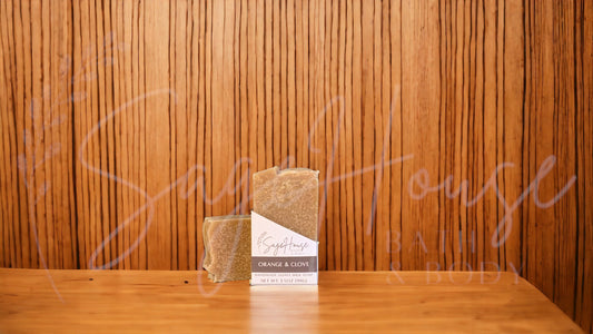 A tan bar of soap in a white labeled box, on a wood surface.