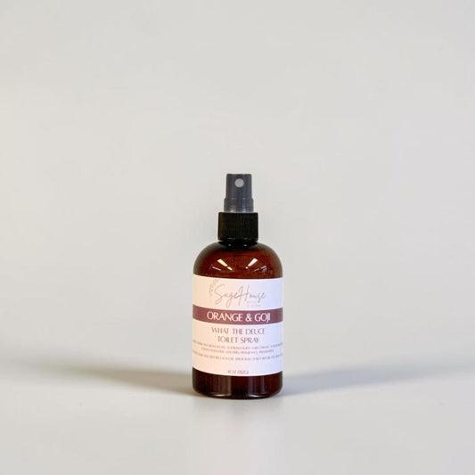An amber spray bottle with black spray nozzle and white label, standing on a light gray surface against a light gray background.