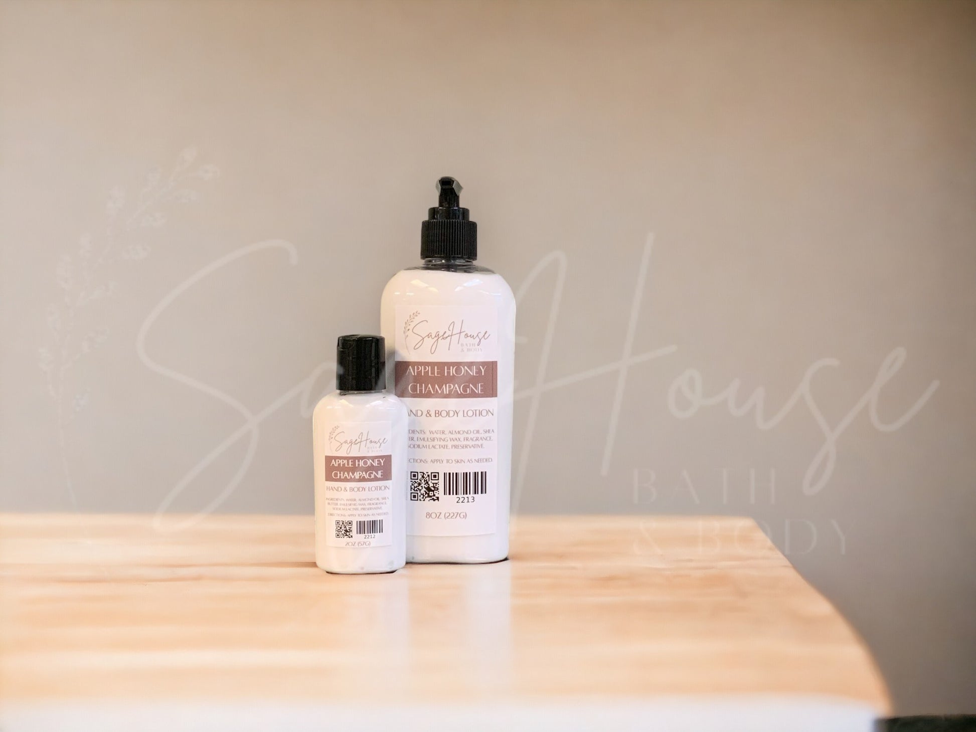2 sizes of bottles of lotion, sitting on a wood surface with neutral background