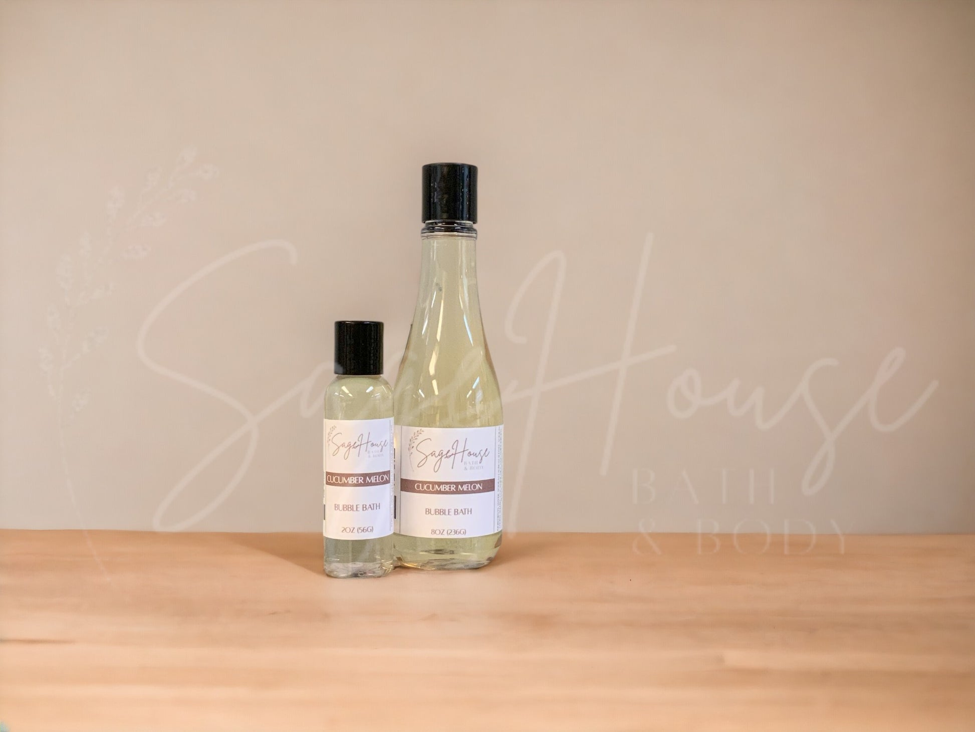 A bottle of Sage House bubble bath, labeled 'cucumber melon'. Placed on a wooden surface.