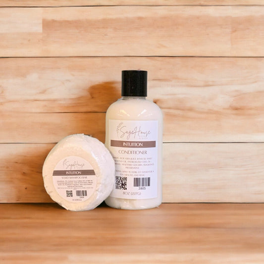 An Intuition shampoo bar & bottle of conditioner on a wooden surface.
