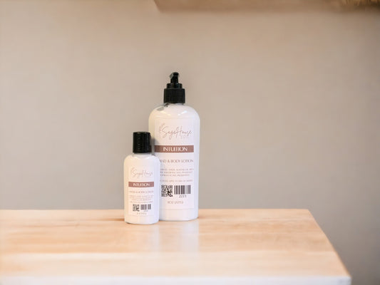 Two bottles of lotion with black caps on a light wooden surface with a tan background