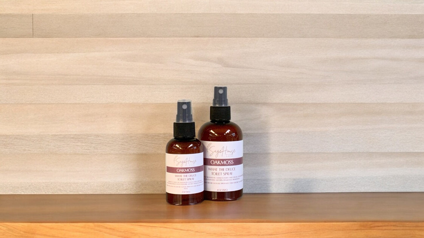 2 Amber colored spritz bottles with oakmoss labels, on wood surface