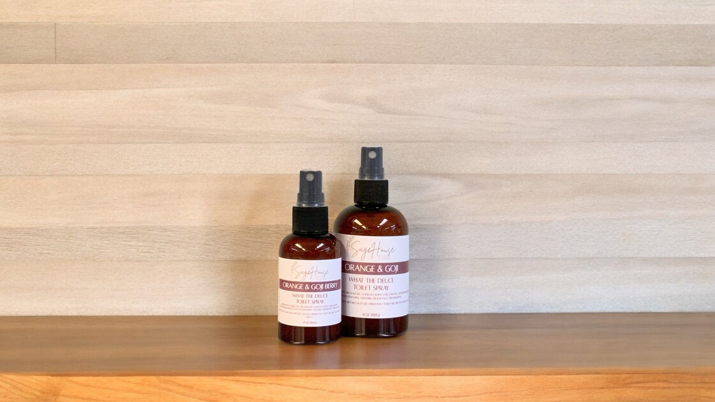 2 Amber colored spritz bottles with orange and goji labels, on wood surface